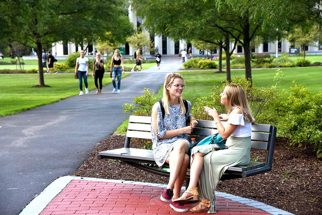 Students sitting on bench at Utica Campus