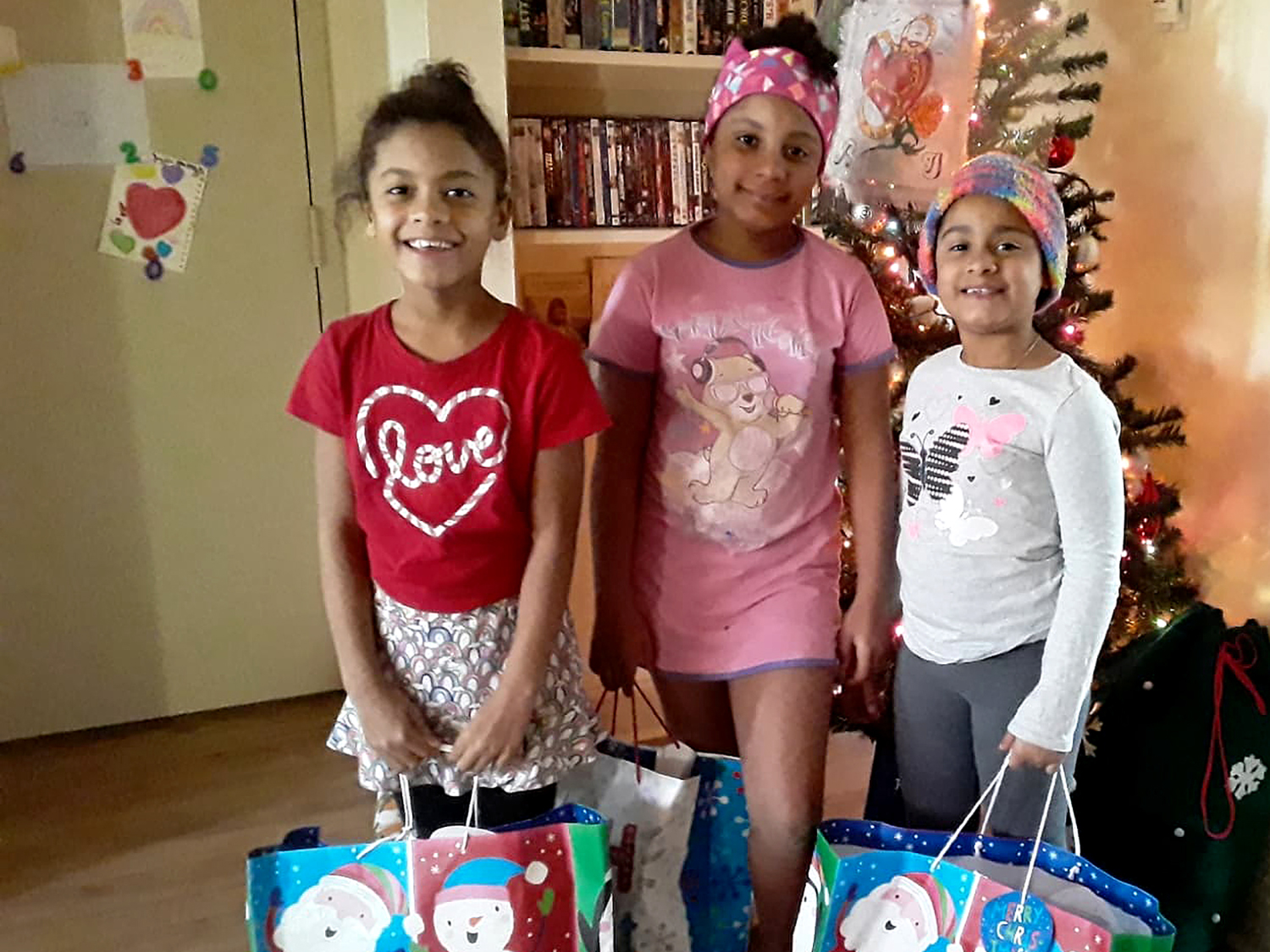 Children smiling, holding the gifts they received from Kidz N Coaches.