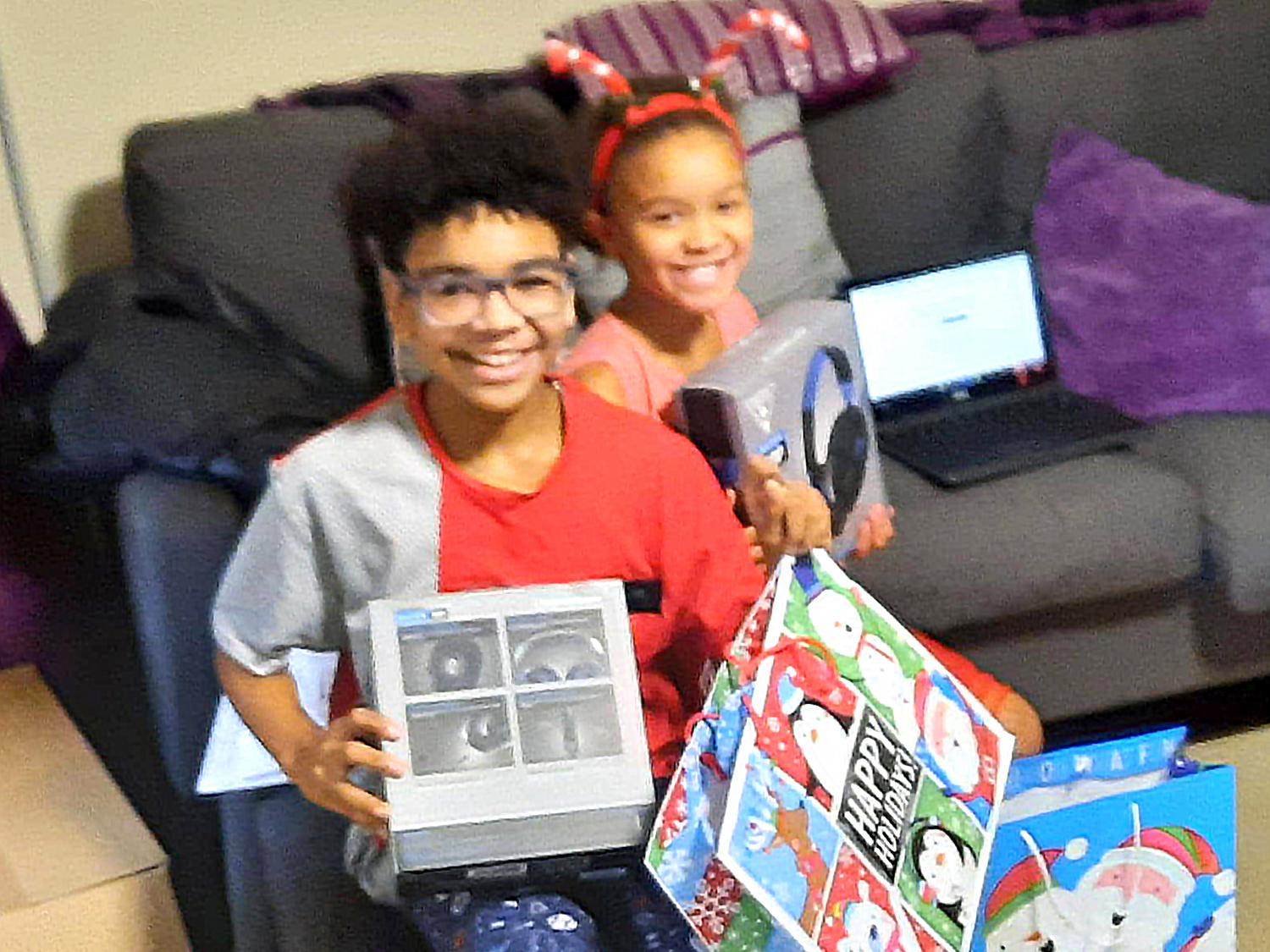 Children smiling, holding the gifts they received from Kidz N Coaches.