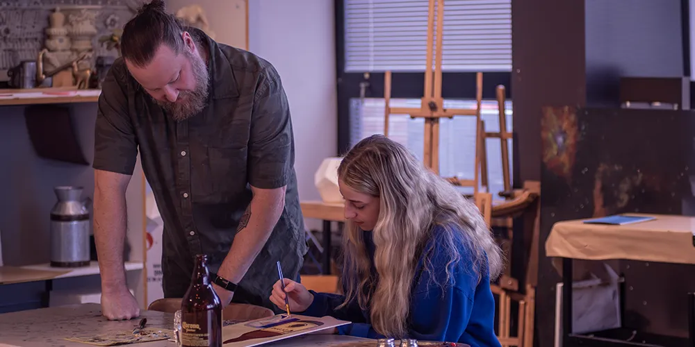 Art students observing painting technique demostration in a classroom