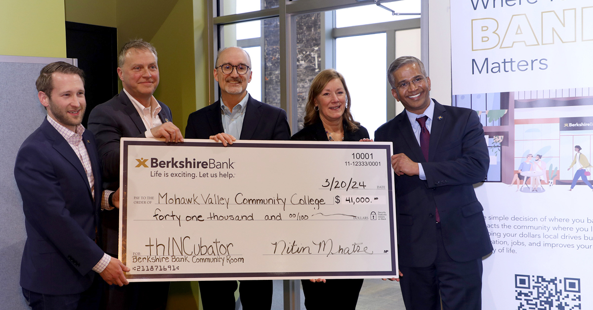 Five people, smiling, holding big check at event